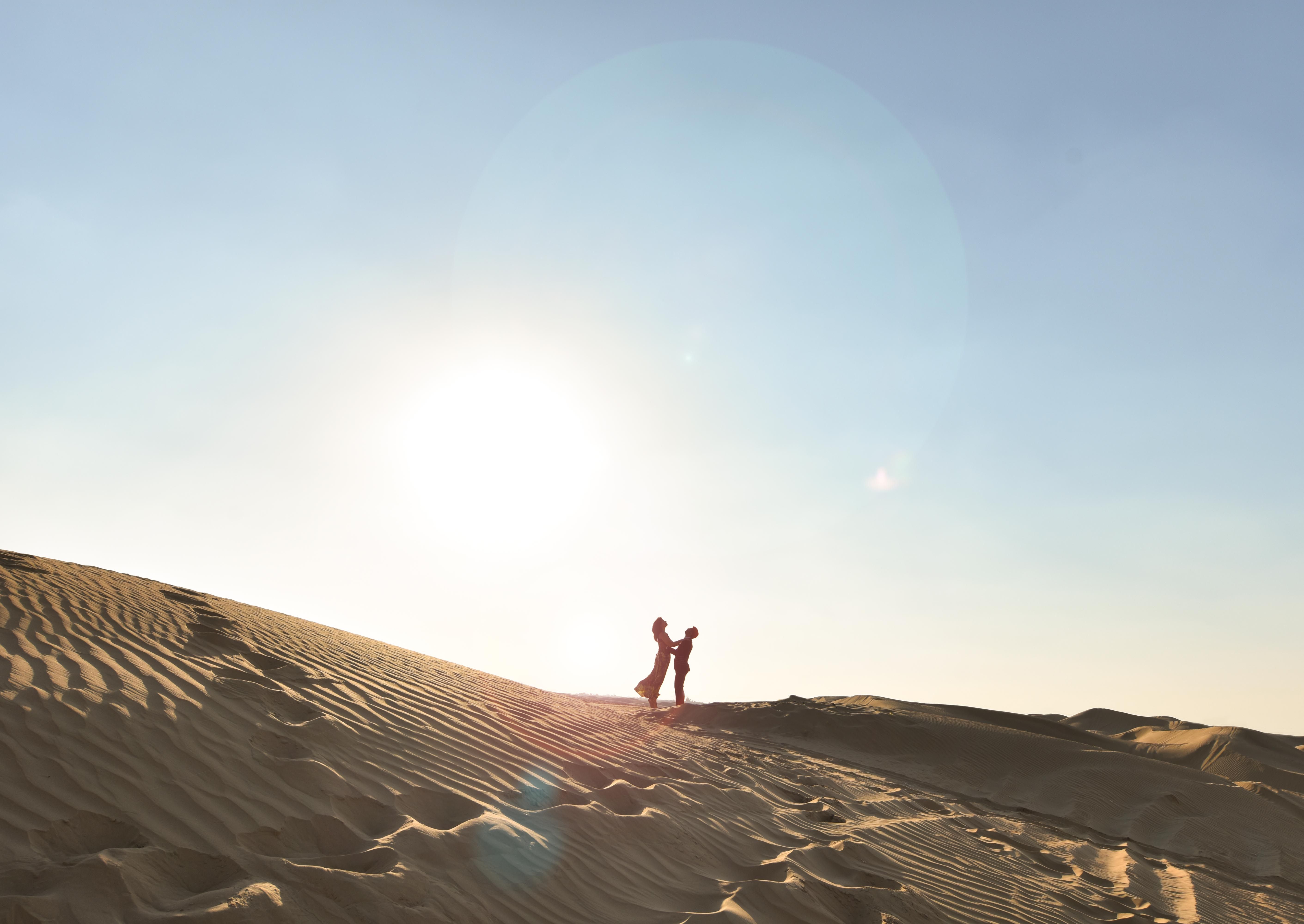 Travelers walking through golden desert dunes near Dubai in warm sunshine.