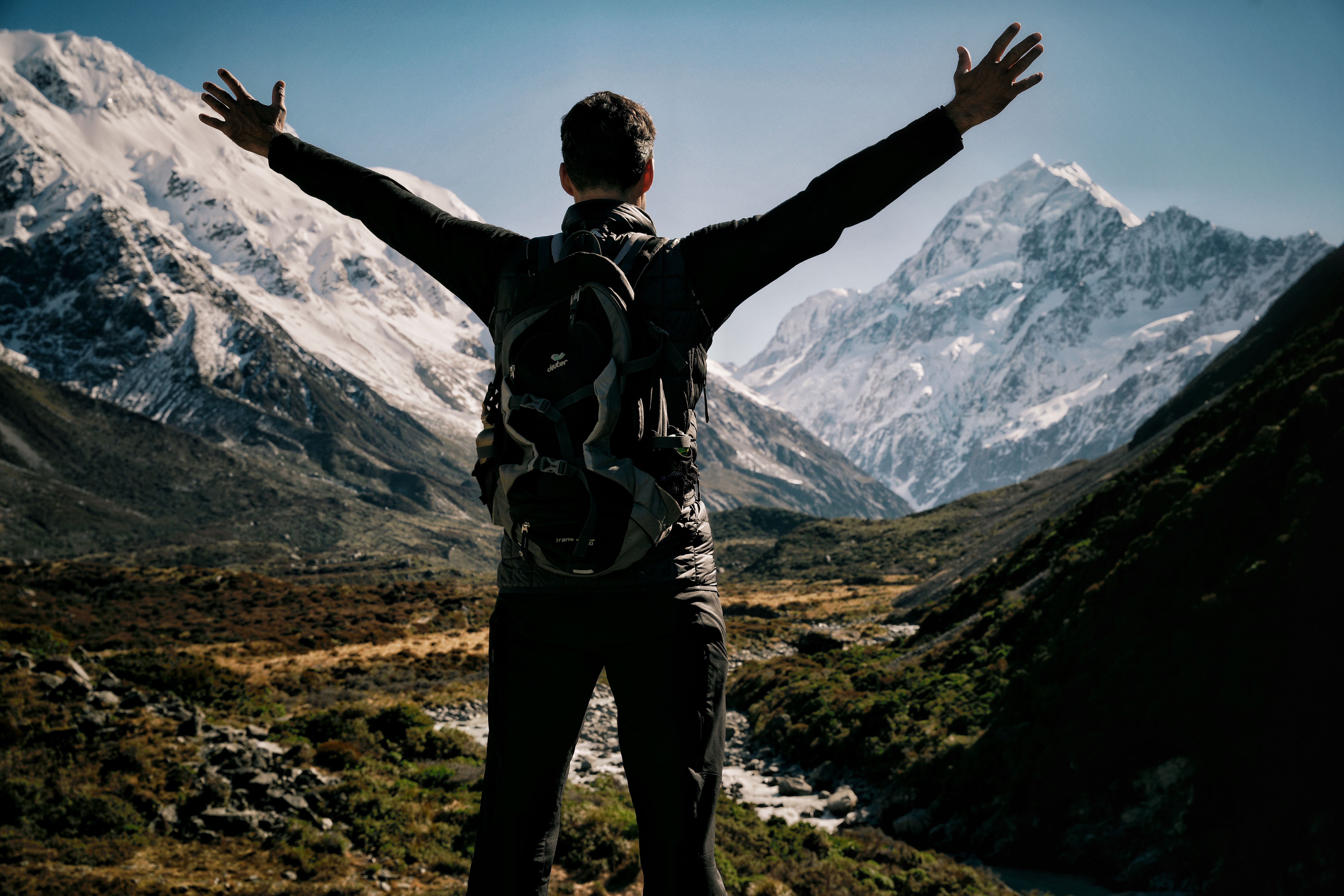 Hiker taking in a dramatic snowy mountain view in New Zealand.